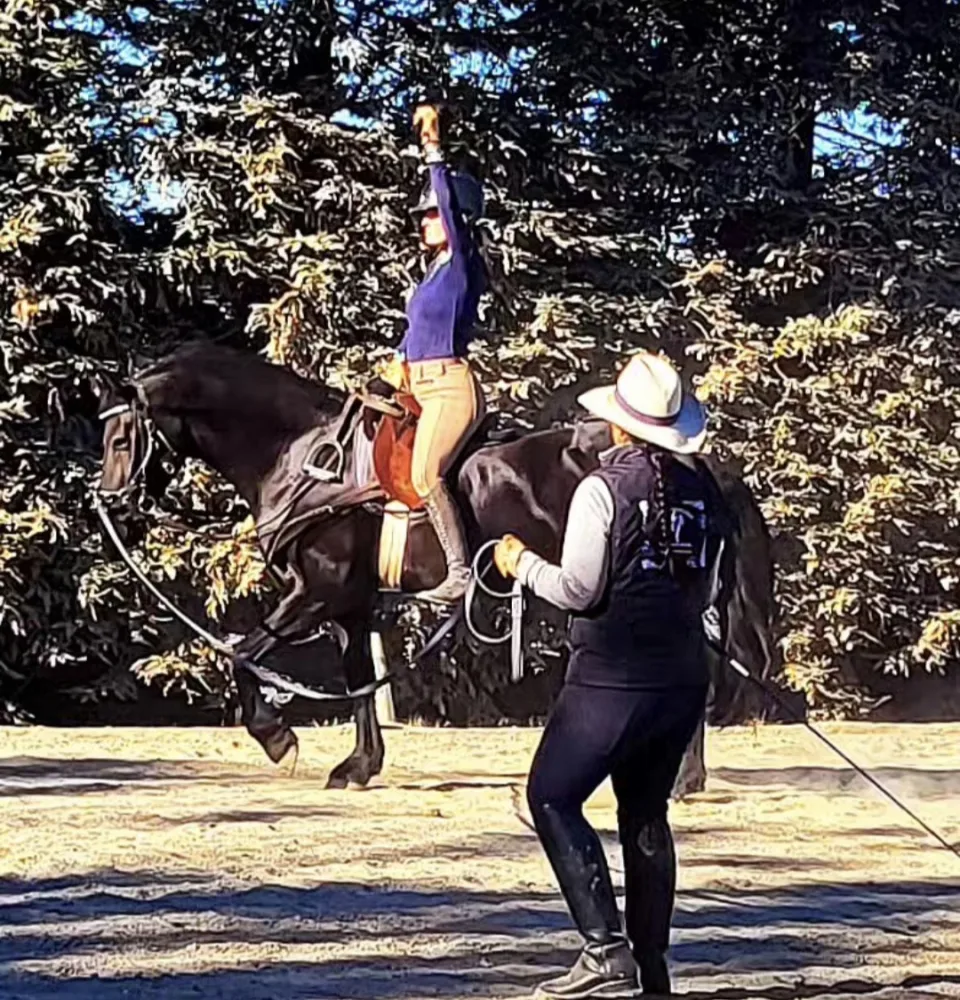 A rider on a dark horse working on the lunge with Tressa Boulden