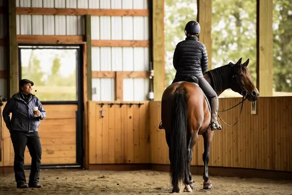 Marika halted on her mare Senja during a lesson while Tressa watches