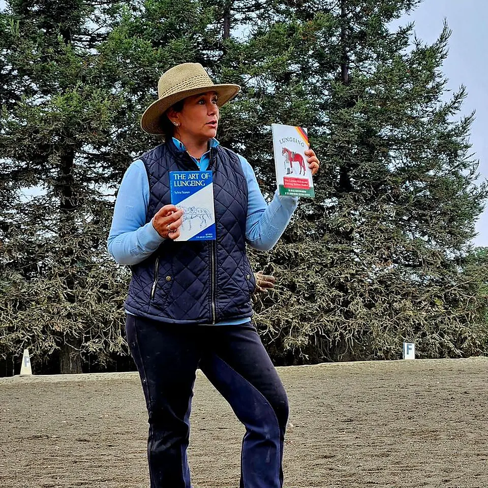 Tressa Boulden teaching a seminar in the arena, holding an open book